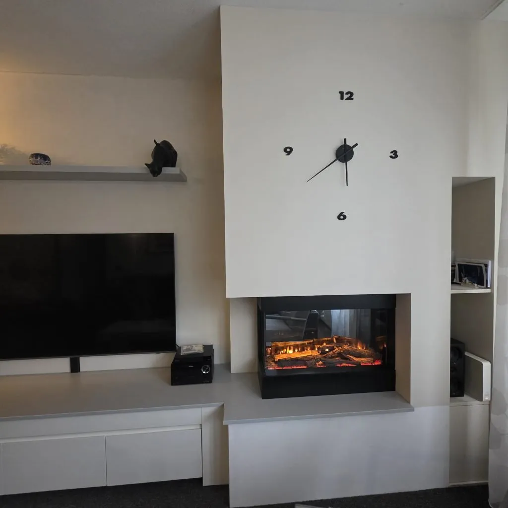 Strakke lichte haardombouw met tv-meubel, greeploze kasten en open nis in Uitgeest